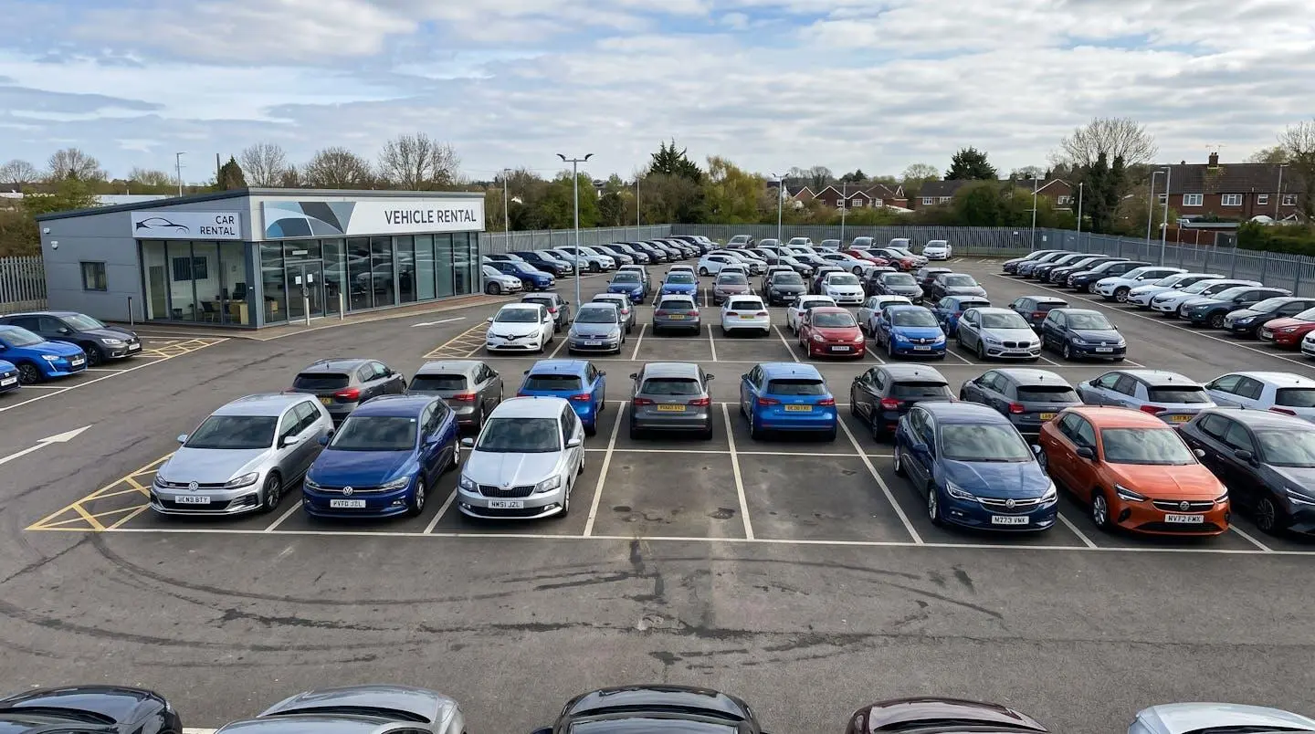Contemporary vehicle rental lot with cars parked in organised rows showing visible empty parking spaces during business hours